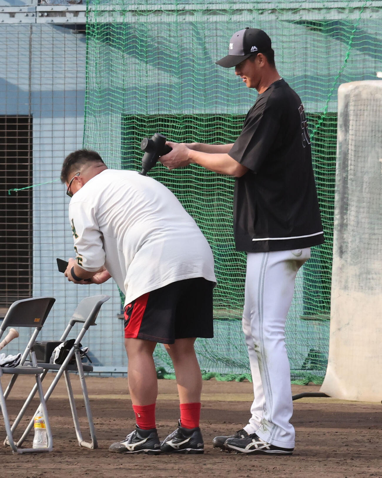 打撃練習の合間にソフトバンク秋広は山川をマッサージガンを使って疲労回復に努める（撮影・梅根麻紀）