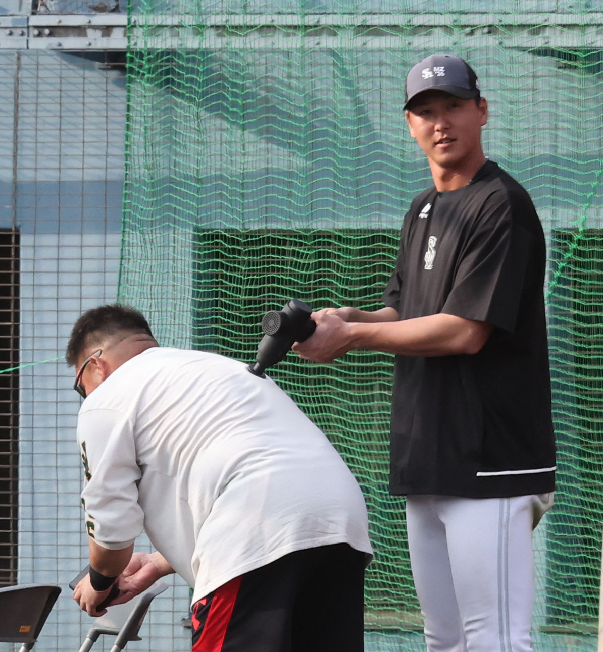打撃練習の合間にソフトバンク秋広は山川をマッサージガンを使って疲労回復に努める（撮影・梅根麻紀）