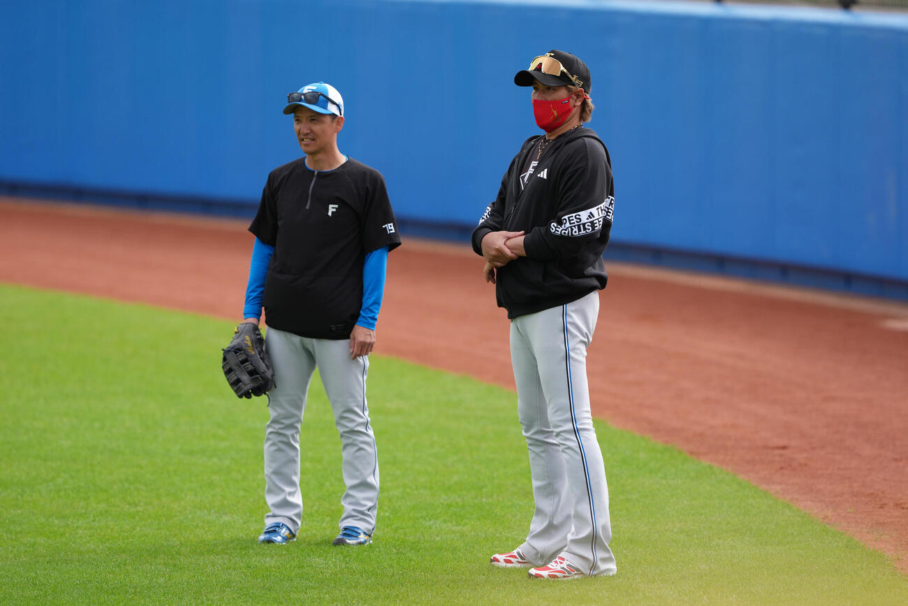 練習中、日本ハム松本コーチ（左）と会話を交わす新庄監督（撮影・足立雅史）