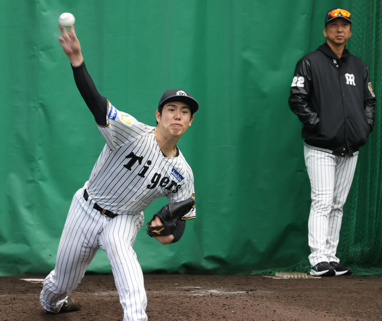 17日、ブルペンで投球する阪神石黒。右は藤川監督