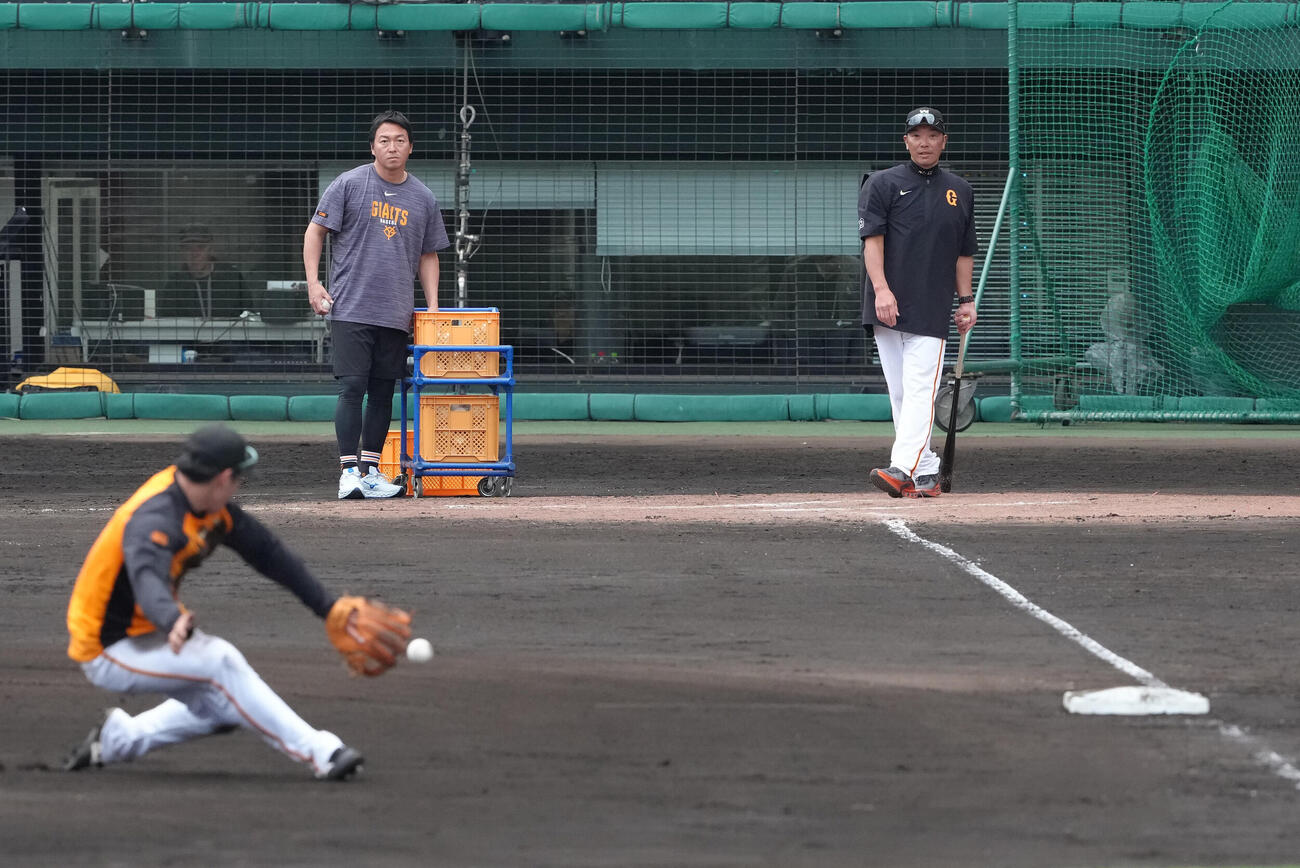 全体練習後、巨人石塚（手前）らにノックを行う巨人阿部監督（右）。左は長野編成本部参与（撮影・足立雅史）