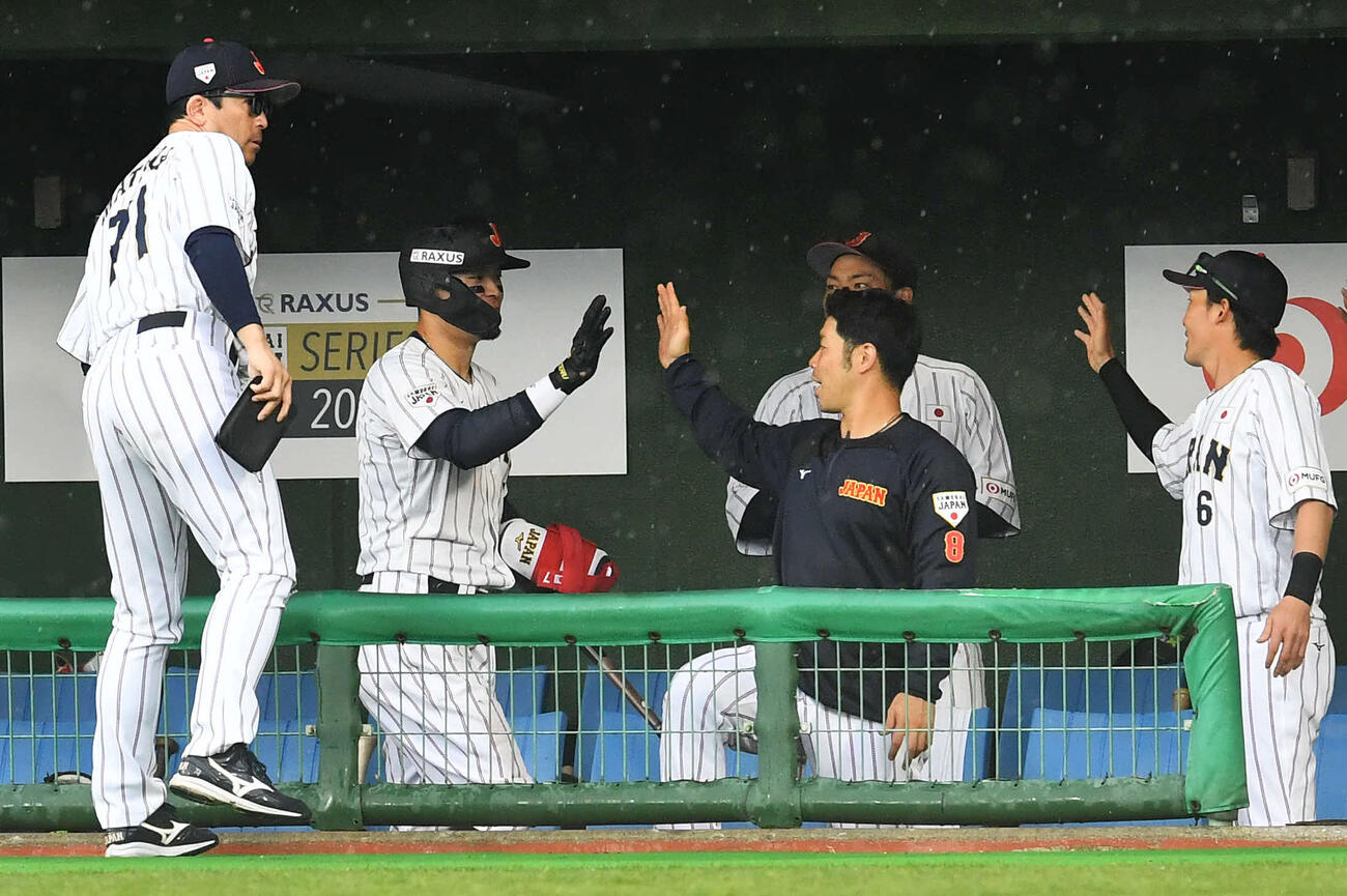日本対ソフトバンク　5回裏日本2死一、三塁、中越え2点適時二塁打を放った佐藤（左から2人目）は代走を送られてベンチへ戻り、右から源田、近藤らナインとタッチを交わす（撮影・岩下翔太）