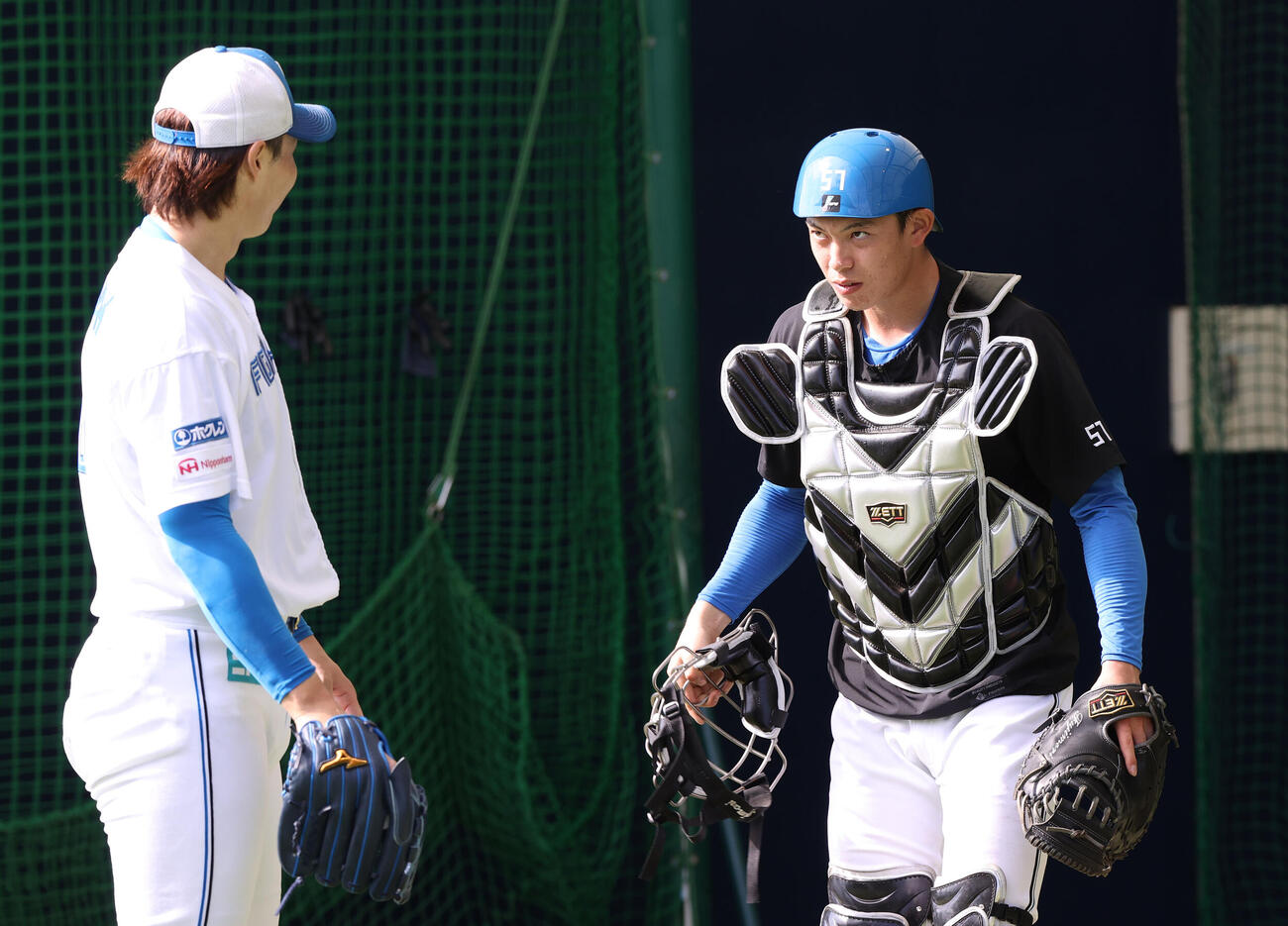 ブルペンで投球を終えた日本ハム山崎（手前）と話す藤森（撮影・上山淳一）