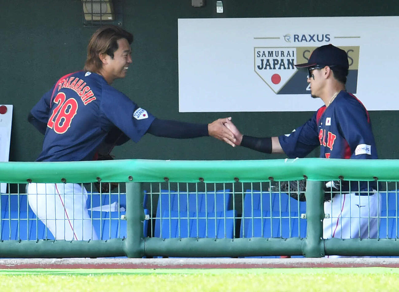 日本対ソフトバンク　5回裏終了後、ベンチで牧原（右）と笑顔でタッチを交わす高橋（撮影・岩下翔太）
