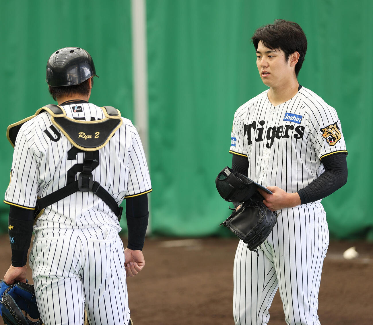 ブルペンで投球を終えた阪神石黒（右）は梅野と話す（撮影・上山淳一）