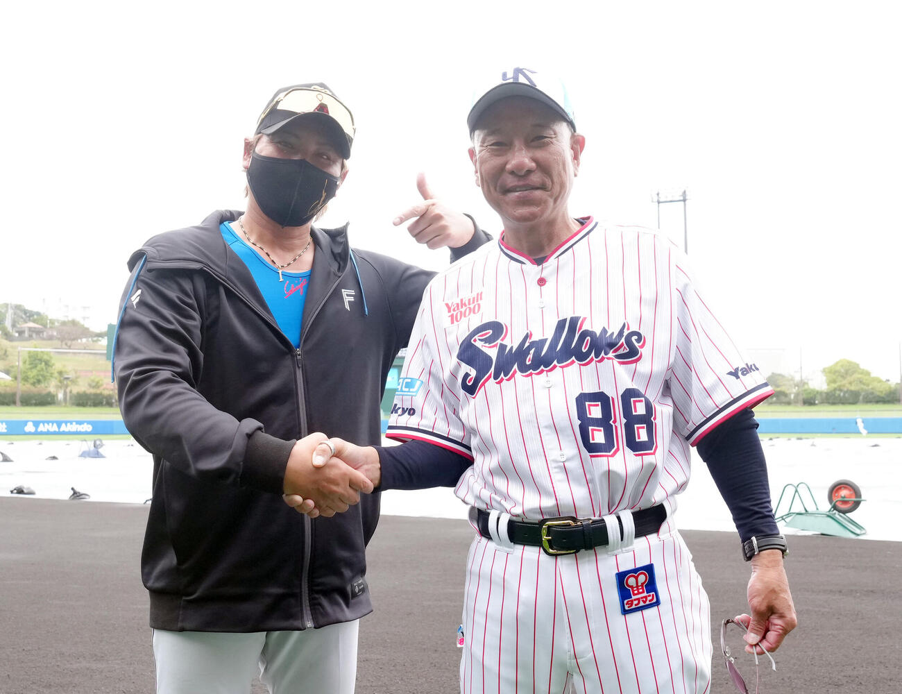 練習中、笑顔で握手を交わす日本ハム新庄監督（左）とヤクルト池山監督（撮影・足立雅史）