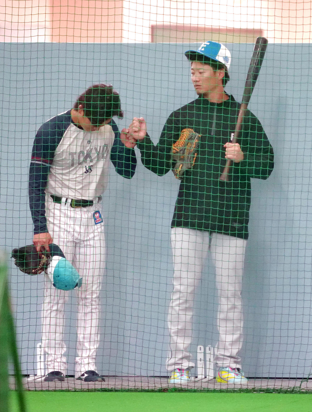 練習中、タッチを交わすヤクルト長岡（左）と日本ハム西川（撮影・足立雅史）