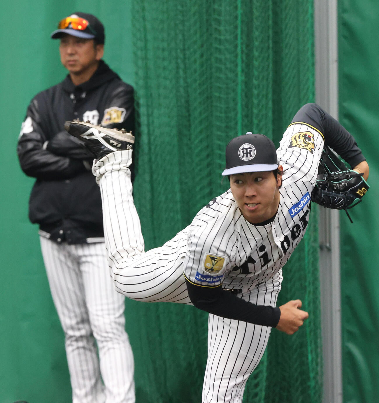 17日、ブルペンで投球する阪神工藤。奥は藤川監督