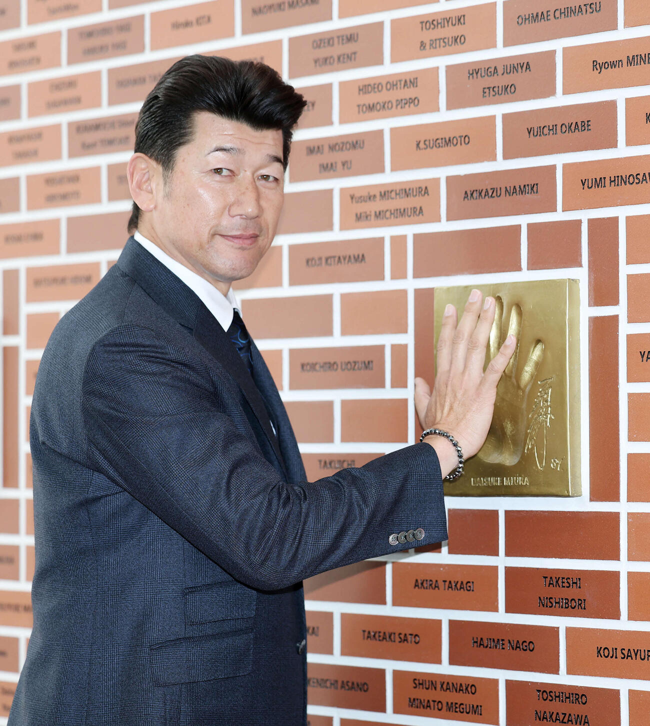 手形の前で写真に納まる三浦アンバサダー（撮影・鈴木正人）　