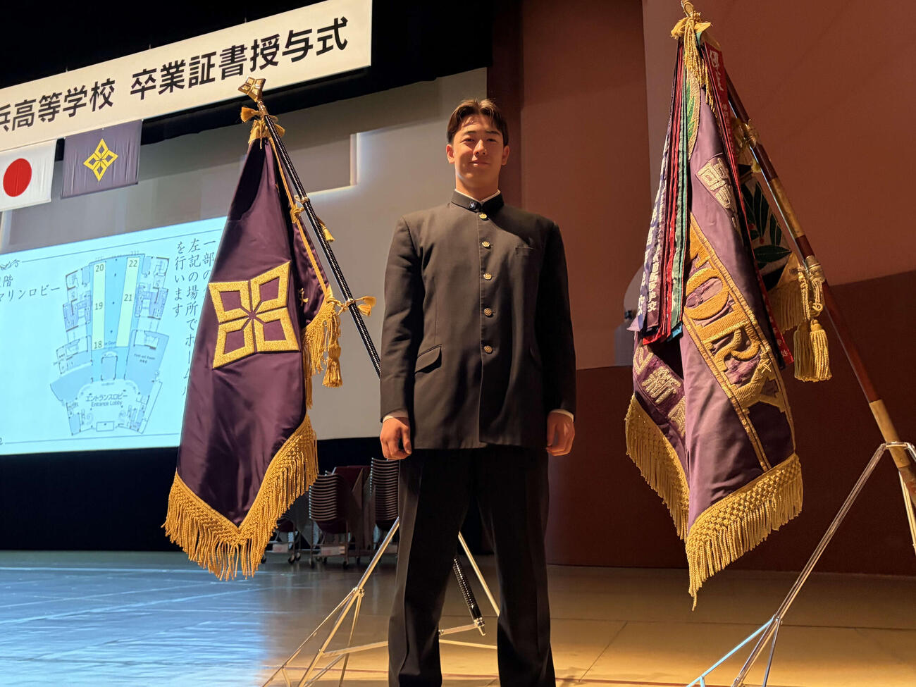 横浜の卒業式で、センバツ優勝旗の前で写真に納まるロッテの奧村頼（撮影・保坂淑子）