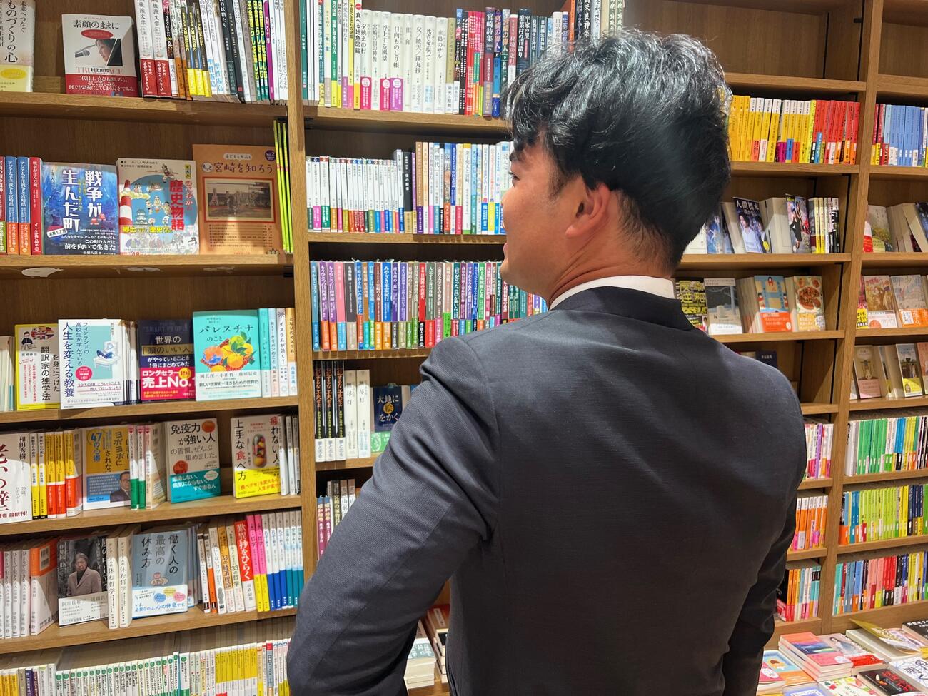 宮崎空港売店の書籍コーナーで本を選ぶ西武是沢（撮影・金子真仁）