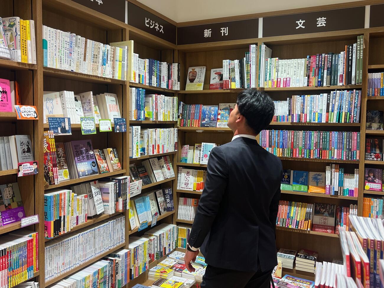 宮崎空港売店の書籍コーナーで本を選ぶ西武是沢（撮影・金子真仁）