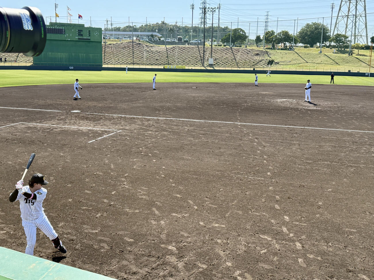 今季ファームの初対外試合に「4番DH」で味方が守備につくイニング間のわずかな時間もベンチ前でバットを振った、阪神浜田（写真左下）（2026年2月14日撮影）