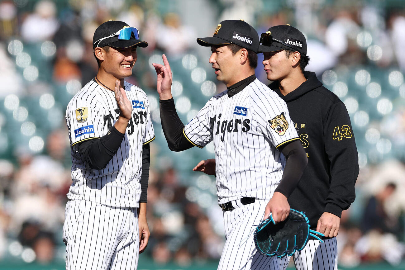 阪神対西武　西武に勝利し、阪神岩崎（中央）らと笑顔でタッチを交わす西純（左）（撮影・前田充）
