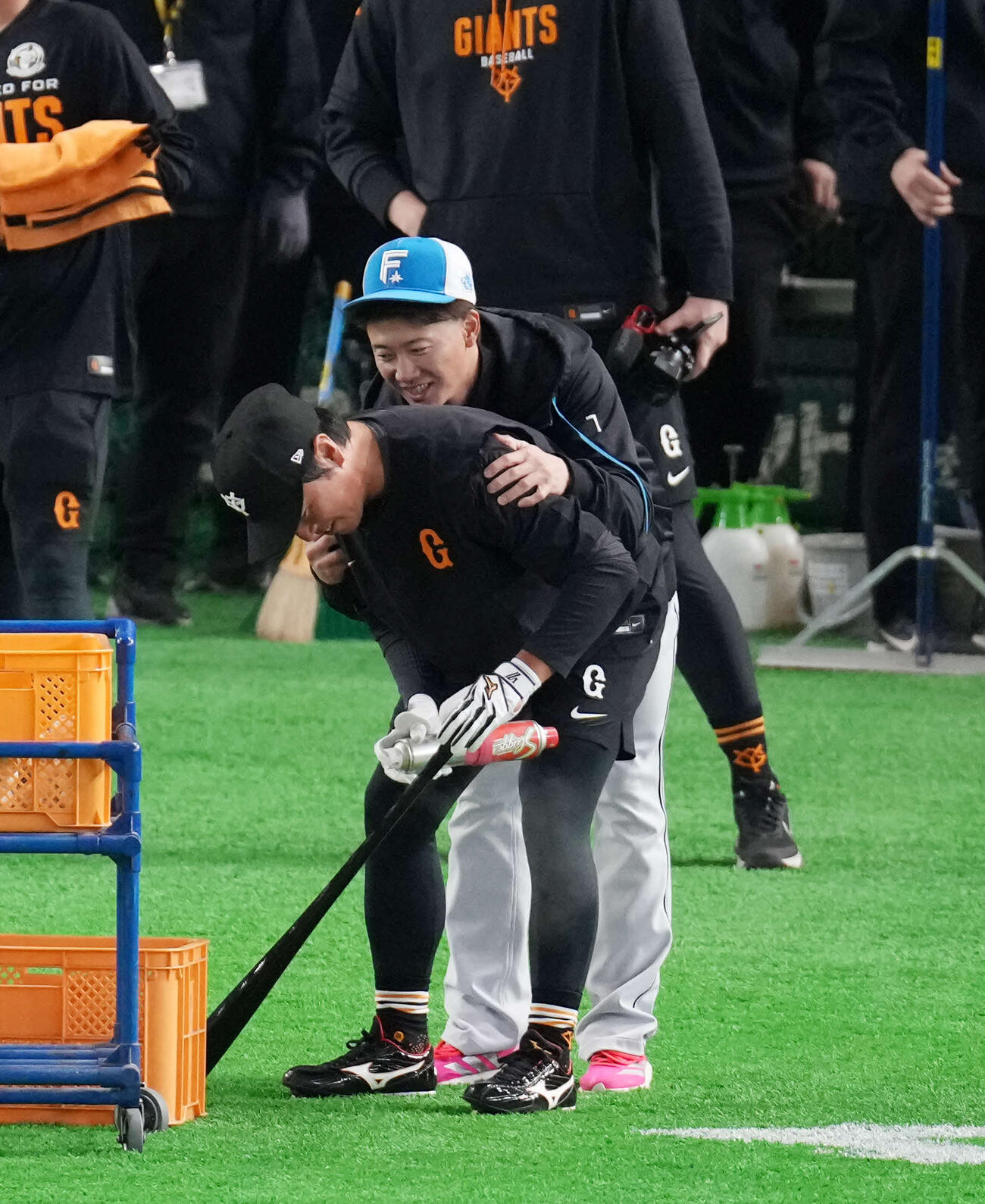 試合前、打撃練習をする巨人長野（下）に抱きつく日本ハム西川（撮影・増田悦実）