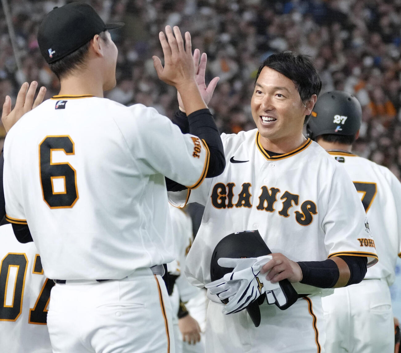 引退試合に巨人の一員として臨み、打席に就いた8回を終え坂本とタッチを交わす長野（共同）