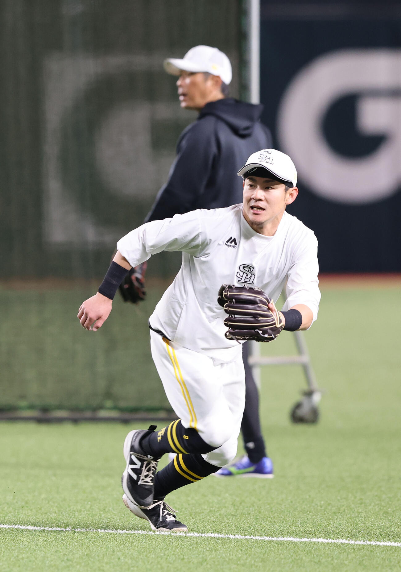 守備練習で軽快な動きを見せる牧原大、後方は小久保監督（撮影・梅根麻紀）