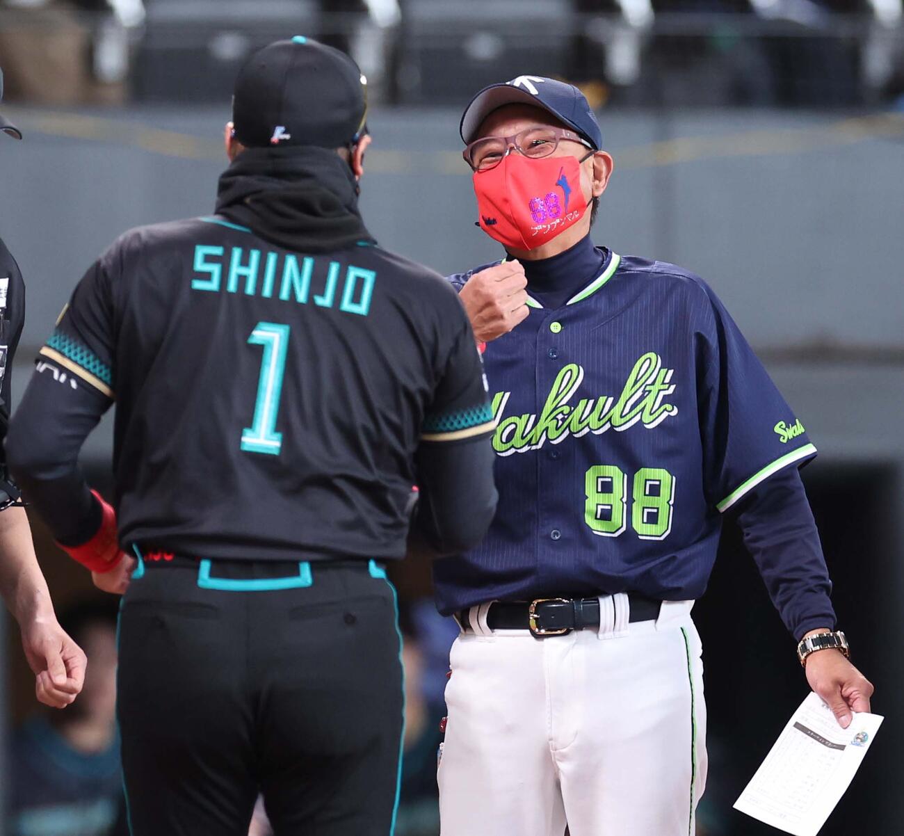 日本ハム対ヤクルト　友人からプレゼントされた赤いマスクつけて、日本ハム新庄監督（左）とメンバー表交換するヤクルト池山監督（撮影・黒川智章）