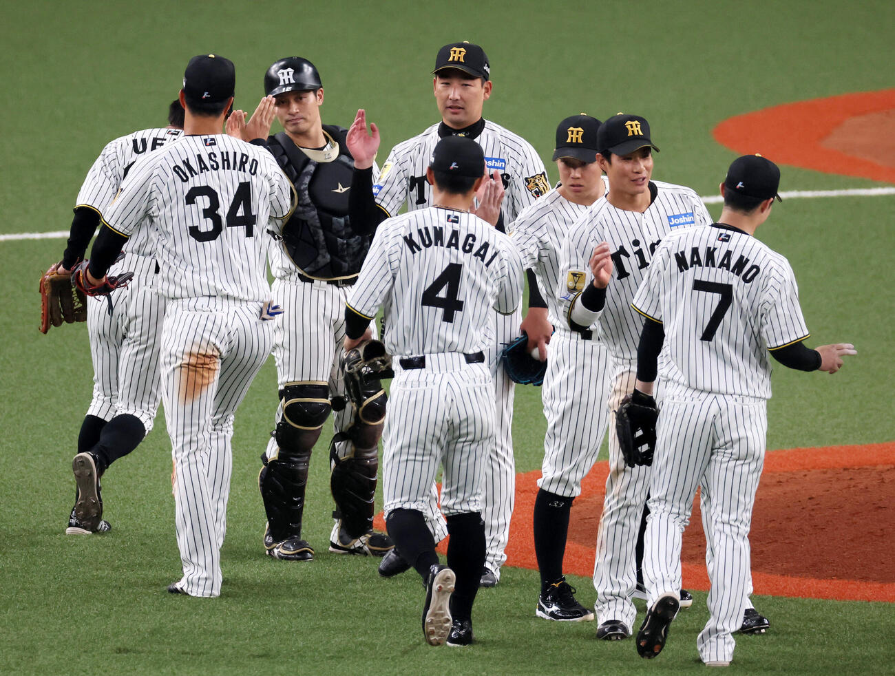 阪神対オリックス　オリックスに勝利しナインとタッチする阪神岩崎、左は坂本（撮影・加藤哉）