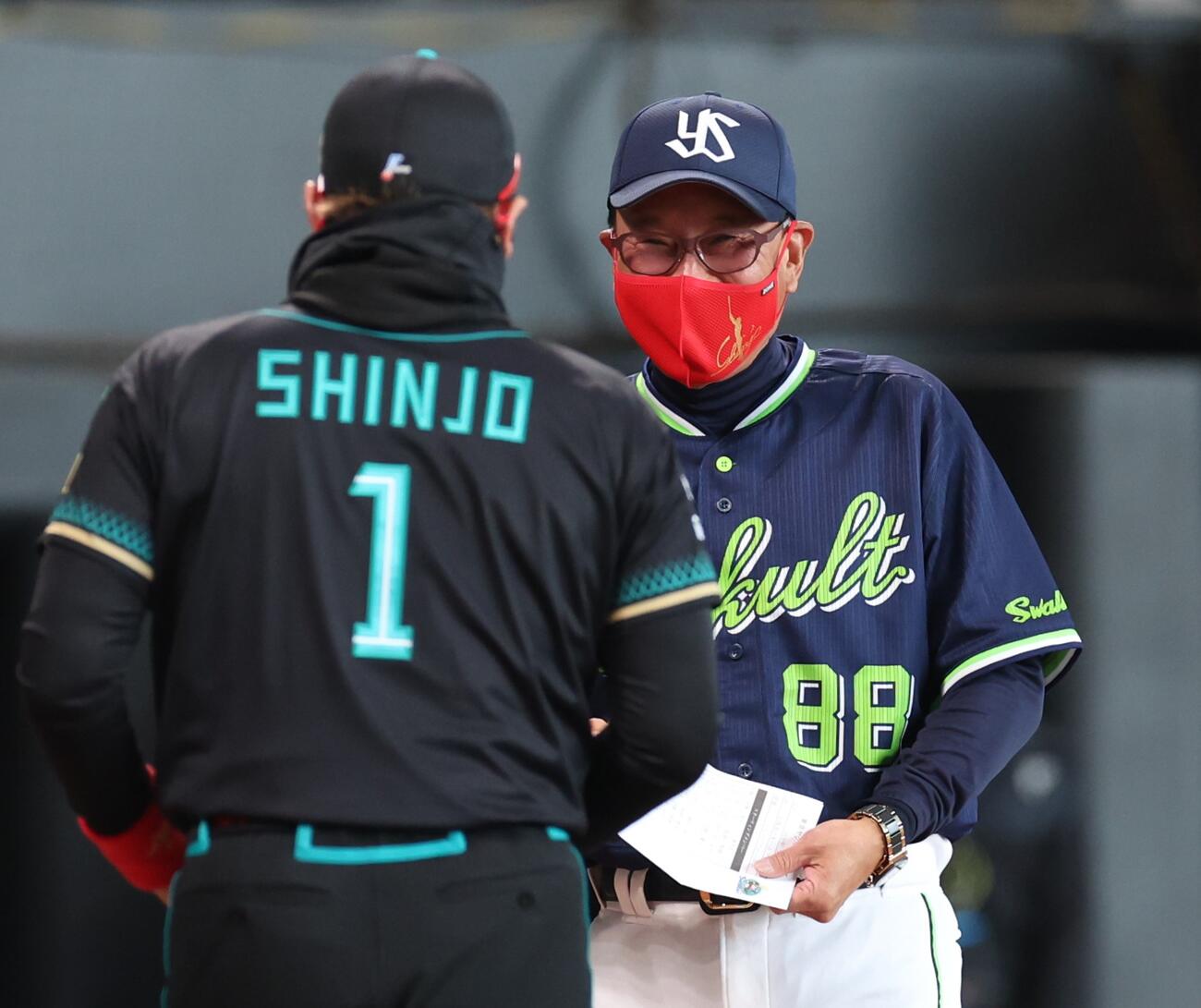 日本ハム対ヤクルト　新庄監督から贈られた赤いマスクを付けメンバー表交換する池山監督（撮影・黒川智章）