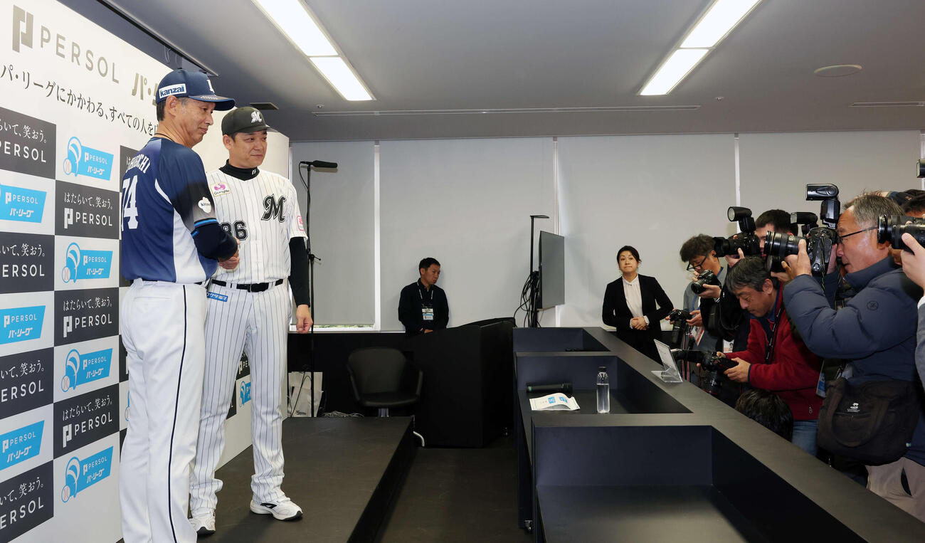 開幕前日記者会見で握手を交わす西武西口監督（左）とロッテのサブロー監督（撮影・宮地輝）