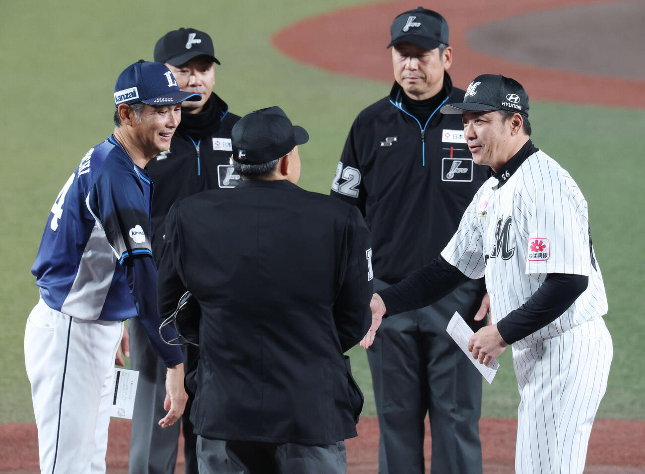 ロッテ対西武　試合前、メンバー表を交換し握手を交わす西武西口監督（左）とロッテのサブロー監督（撮影・宮地輝）