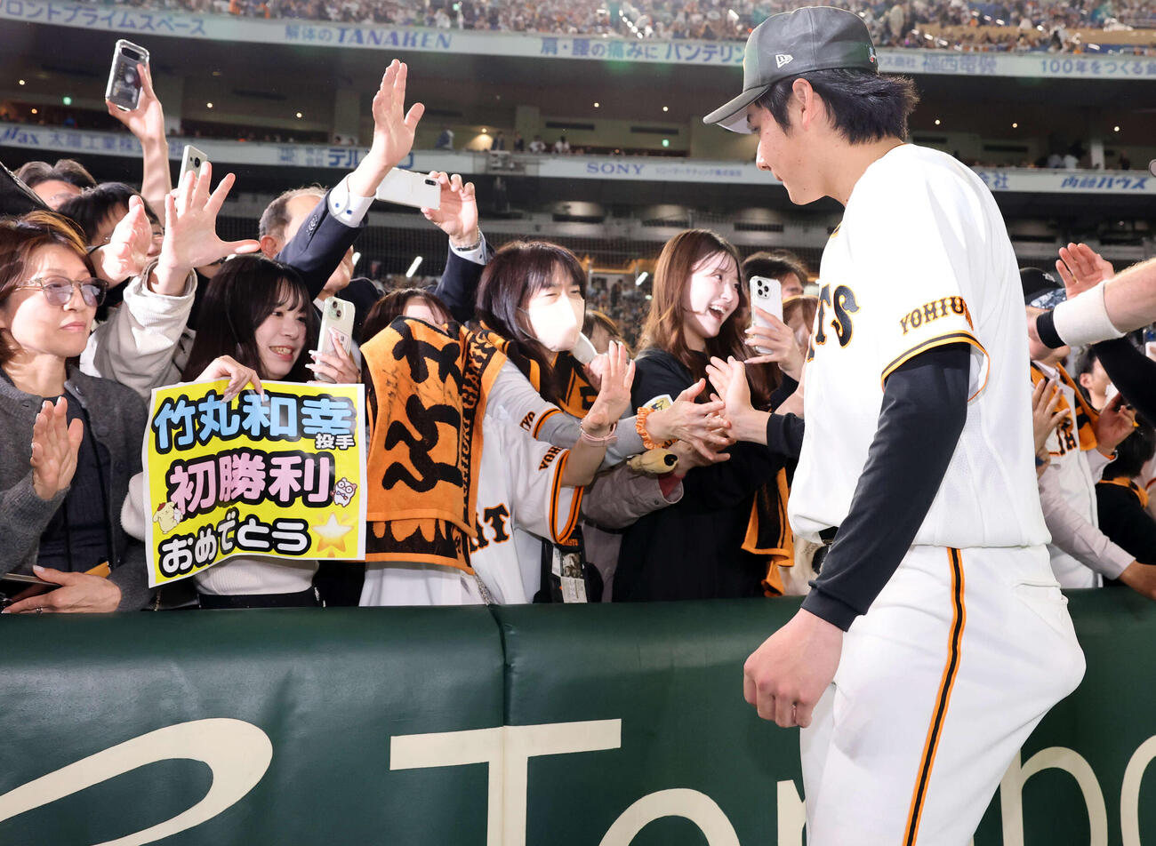 巨人対阪神　開幕戦で球団初となる新人先発初勝利の竹丸は「初勝利おめでとう」のボードを持つファンとハイタッチ（撮影・浅見桂子）