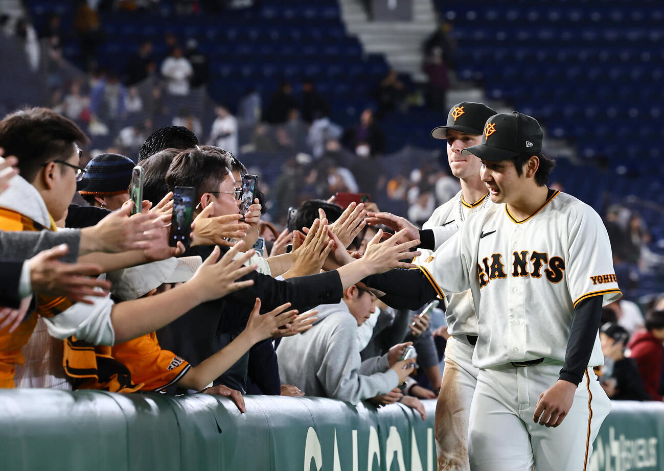 巨人対阪神　プロ初勝利をあげた竹丸（右）と先頭打者本塁打を放ったキャベッジはファンとハイタッチをする（撮影・上田博志）