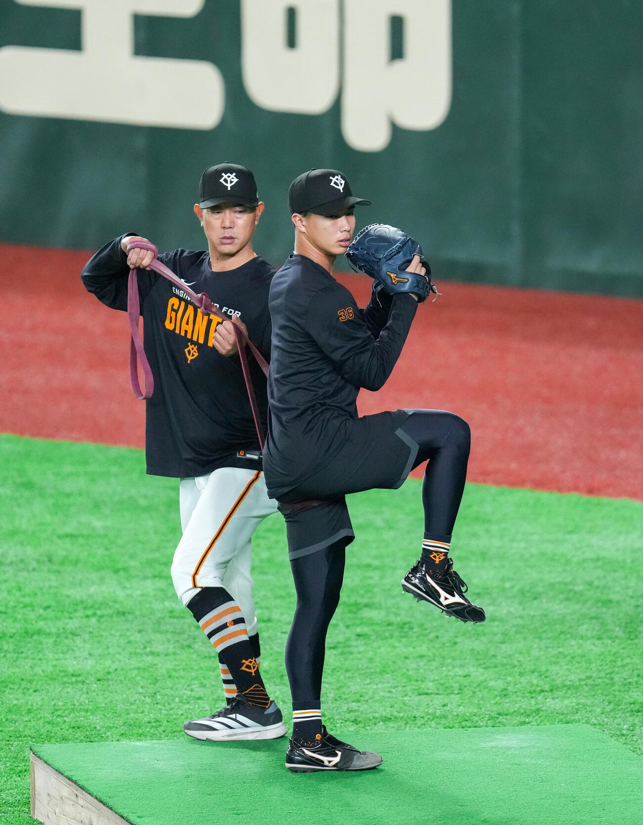 内海哲也投手コーチ（奥）とゴムを使い練習する巨人山城（撮影・増田悦実）