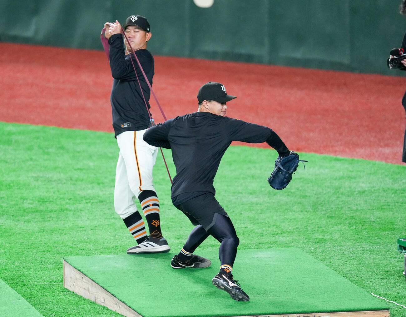 内海哲也投手コーチ（奥）とゴムを使い練習する巨人山城（撮影・増田悦実）
