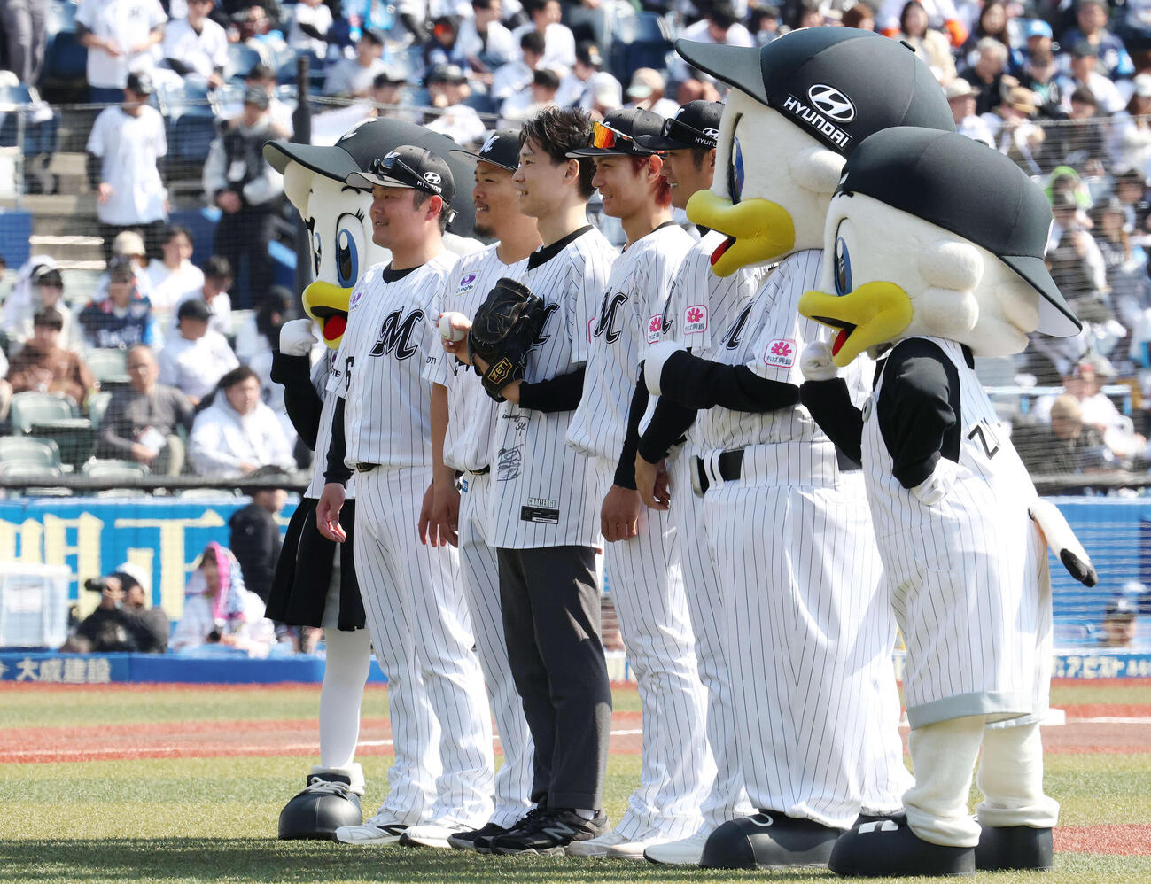 ロッテ対西武　始球式を務めた大阪桐蔭高校野球部OBの福森大翔さん（中央）と記念撮影するロッテの選手とコーチたち（撮影・宮地輝）