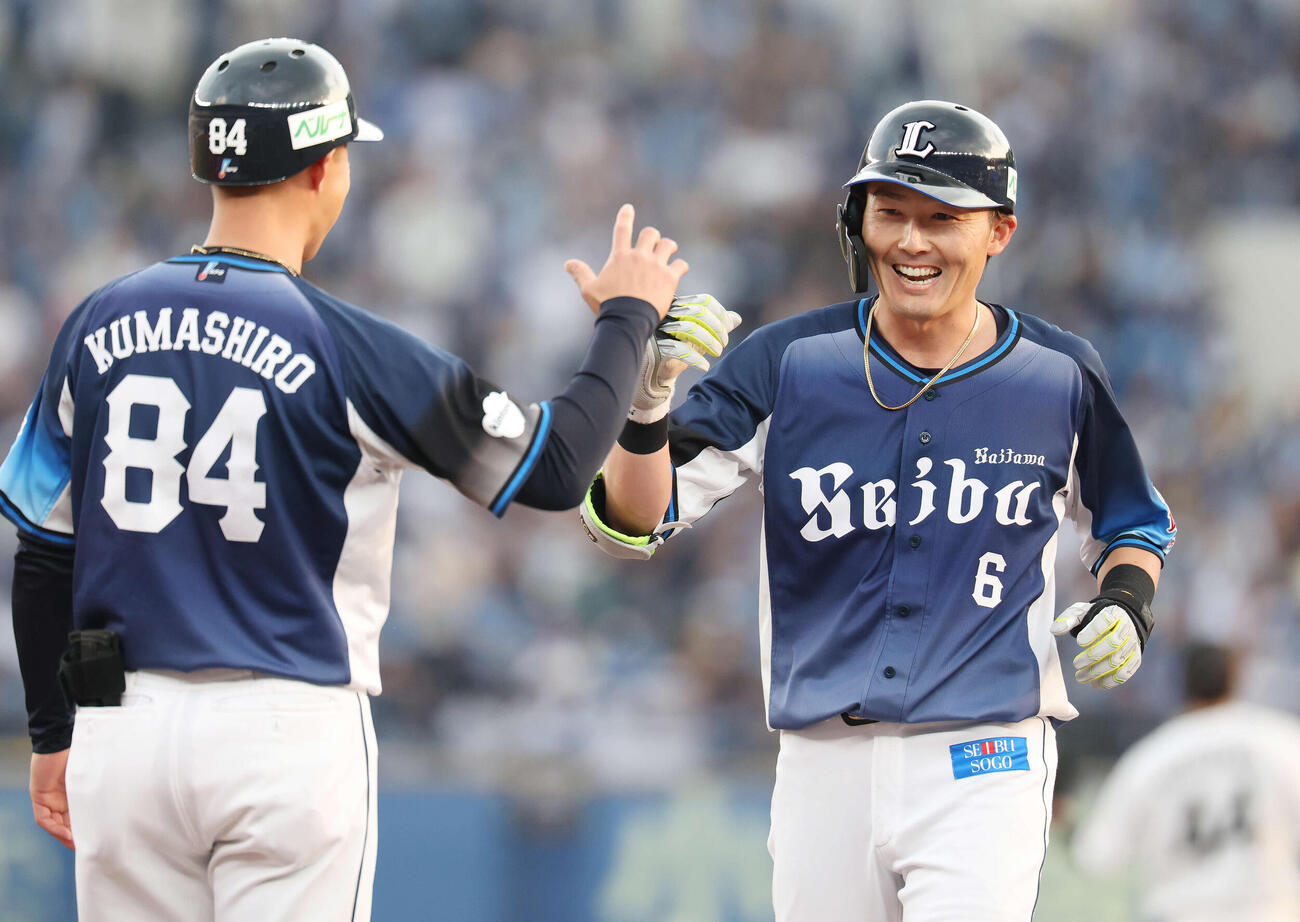 ロッテ対西武　9回表西武1死二、三塁、2点適時打を放ち熊代外野守備・走塁コーチ（左）と笑顔でタッチする源田（撮影・宮地輝）