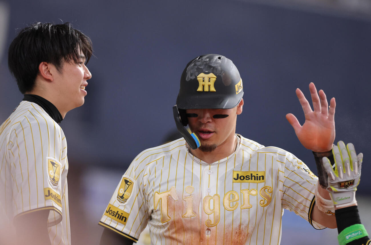 阪神対DeNA 6回裏阪神無死二、三塁、三走佐藤（手前）は高寺の左犠飛で生還しハイタッチする。左は才木（撮影・上山淳一）