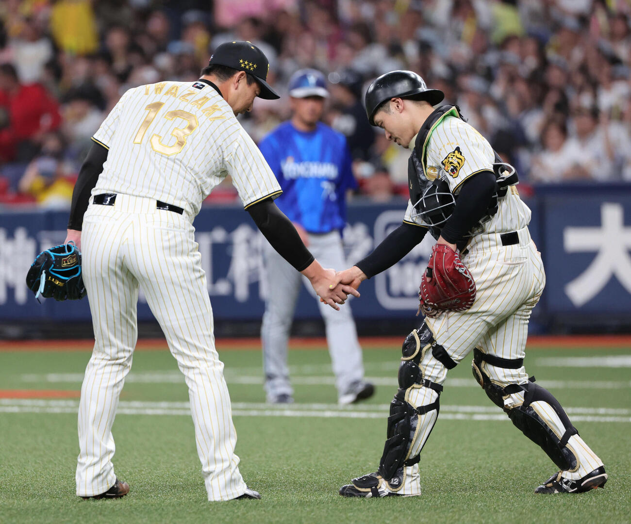 阪神対DeNA 9回表DeNA2死一、二塁、最後の打者を三振に打ち取った岩崎は坂本と握手（撮影・西尾就之）
