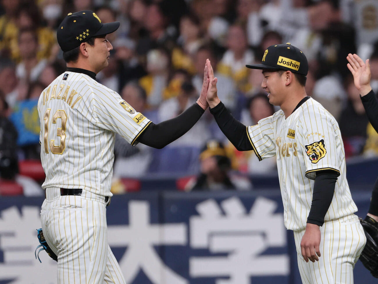 阪神対DeNA　今季初勝利の阪神伊原（右）は最後を締めた岩崎とハイタッチ（撮影・西尾就之）