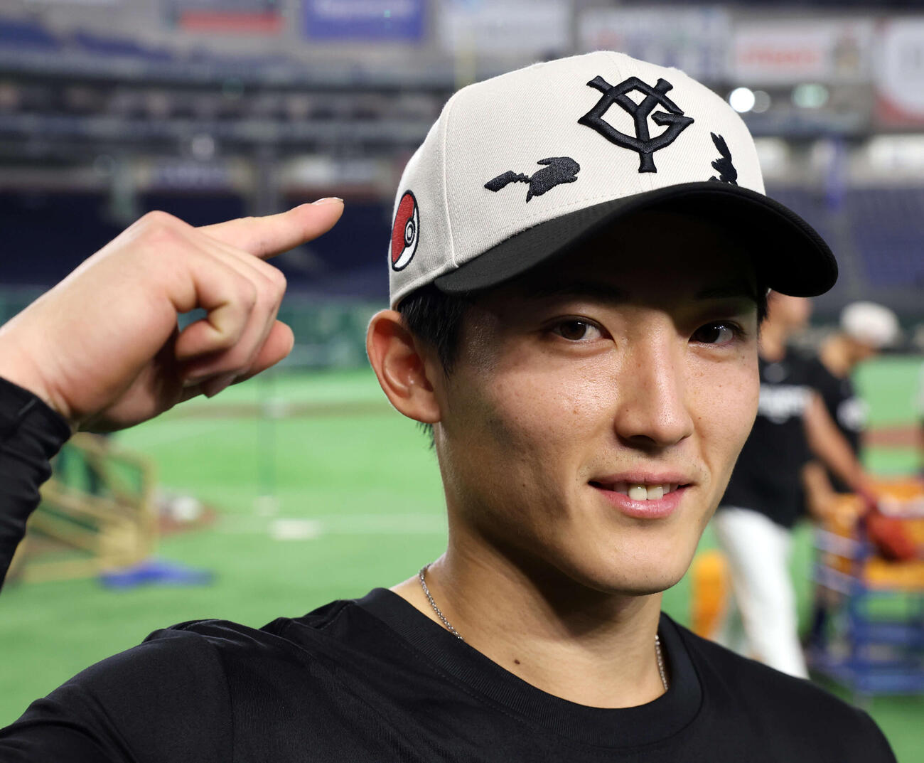 巨人対DeNA　ポケモンデーで、巨人浦田は練習用のコラボキャップを笑顔で指さす（撮影・浅見桂子）
