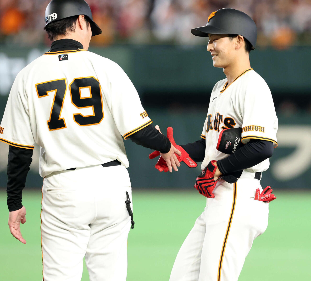 巨人対DeNA 7回裏巨人2死一塁、宇都宮は三塁内野安打でプロ初安打とし、亀井コーチと笑顔で握手（撮影・浅見桂子）