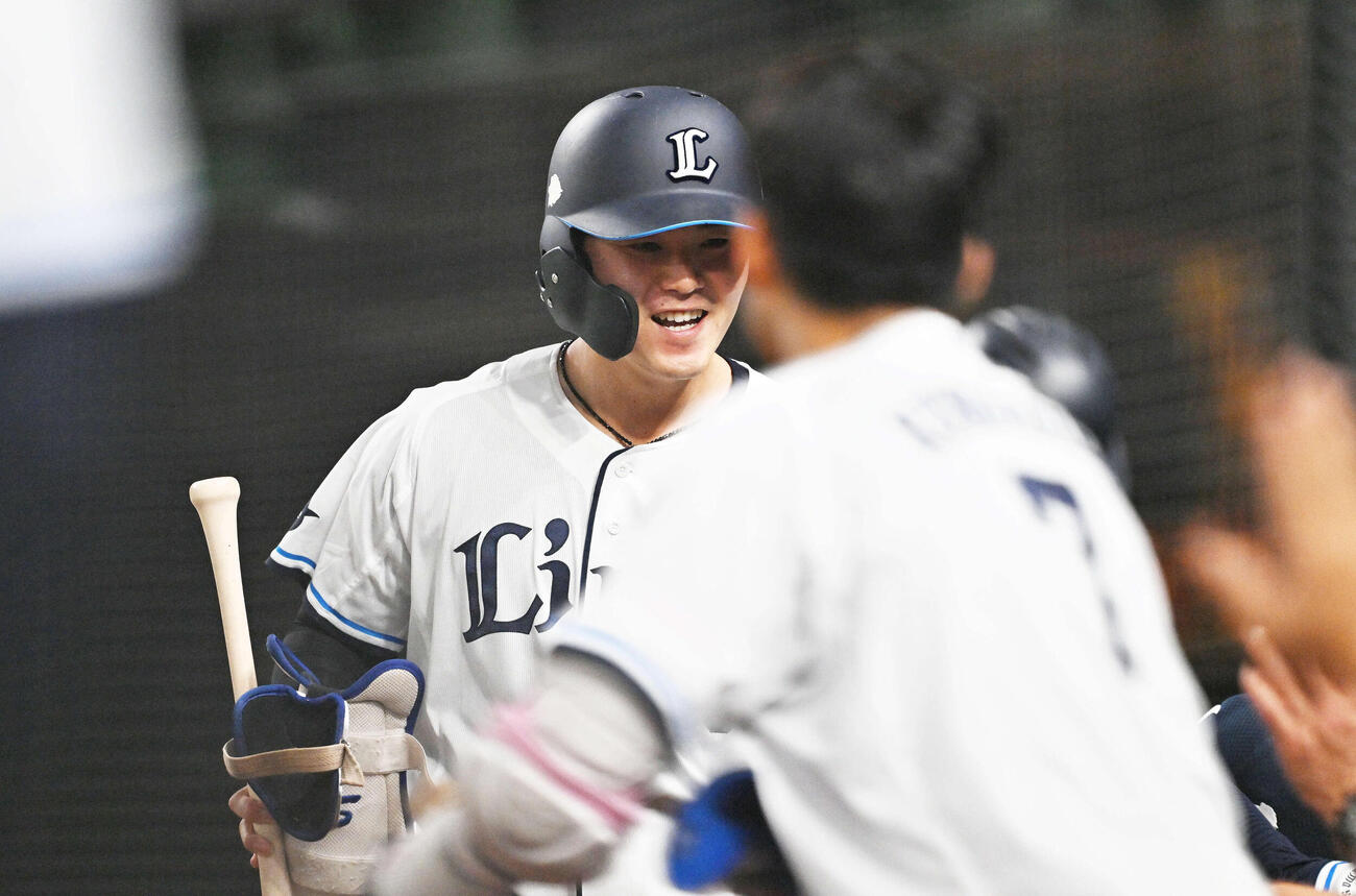 西武対ロッテ　6回裏にプロ初安打を放った秋山はベンチ前でチームメートとタッチをかわす（撮影・滝沢徹郎）