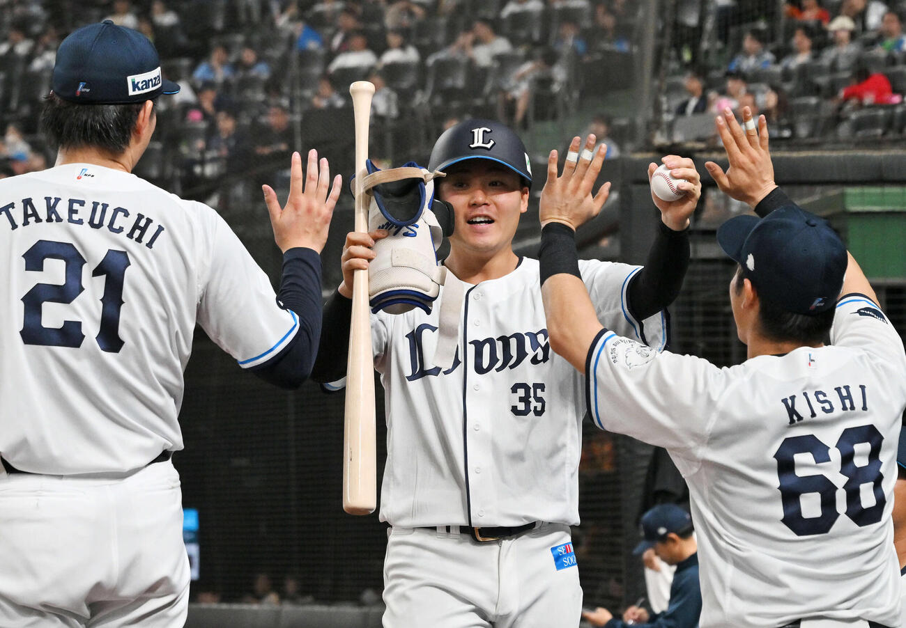 西武対ロッテ　6回裏にプロ初安打を放った秋山（中央）は記念球を手にチームメートとタッチをかわす（撮影・滝沢徹郎）
