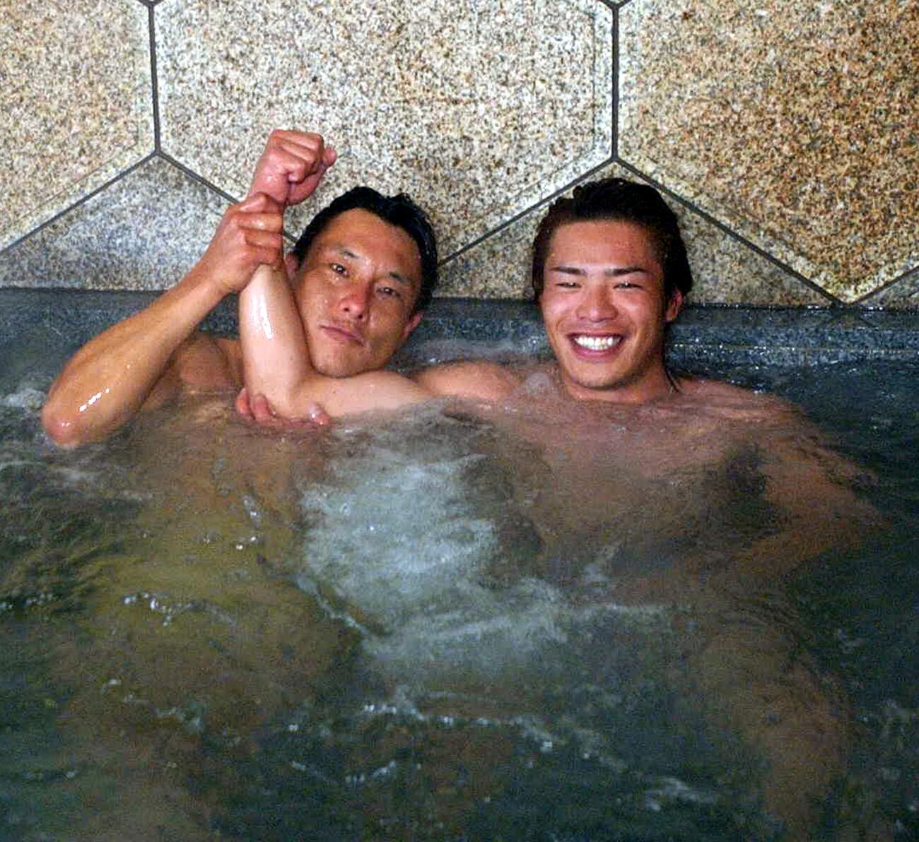 松山市の権現温泉で、昨季限りで引退した池山隆寛（左）から右腕を上げられ笑顔の岩村明憲（2003年1月撮影）
