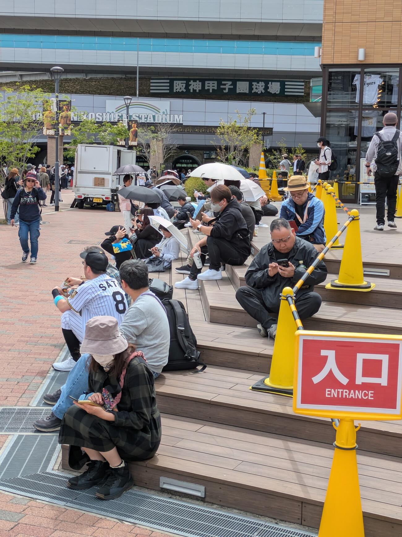 甲子園駅前で携帯を見る人々（撮影・上田博志）
