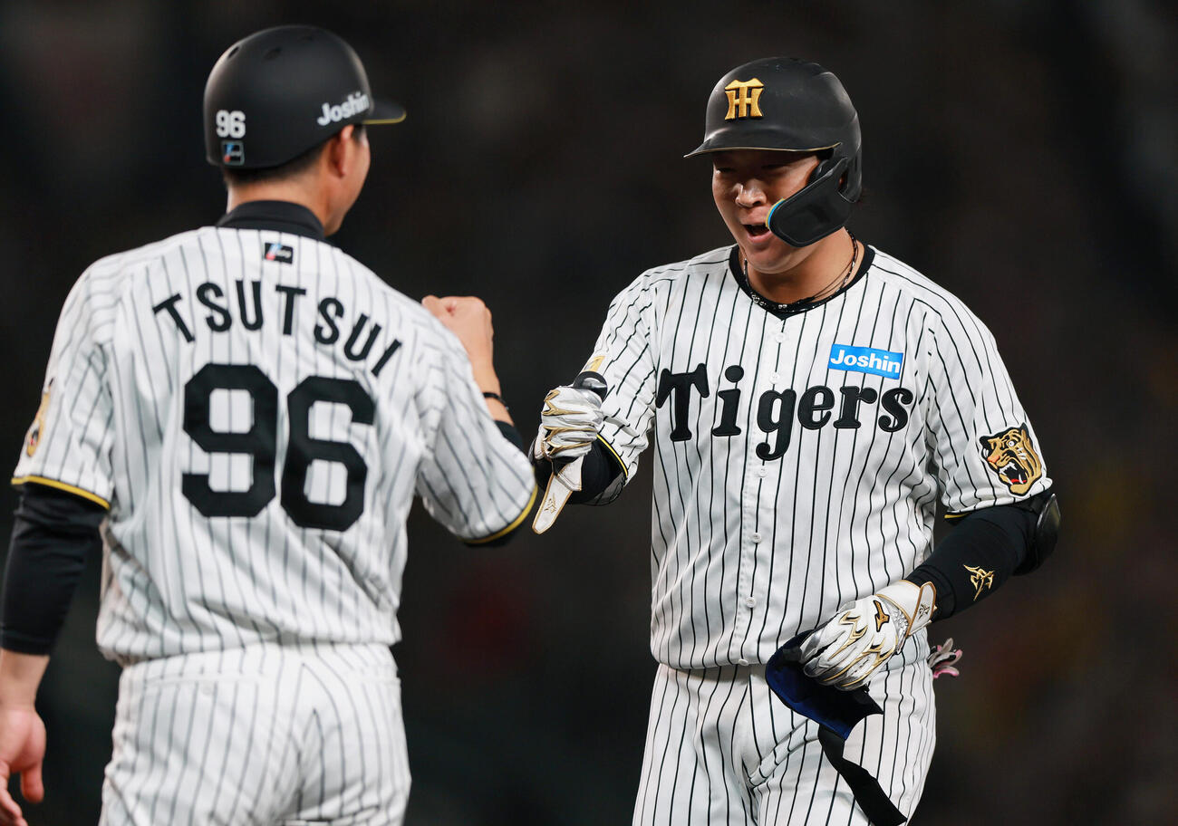 阪神対中日　6回裏阪神無死三塁、大山（右）は適時打を放ち筒井外野守備兼走塁チーフコーチとタッチをかわす（撮影・上山淳一）