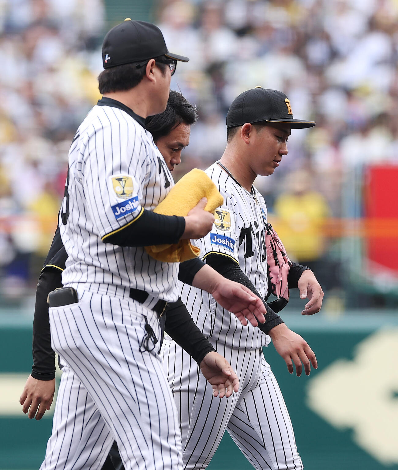 阪神対中日　2回表中日1死一、二塁、トレーナーに付き添われて降板する伊原（右）。手前は安藤投手コーチ（撮影・前田充）