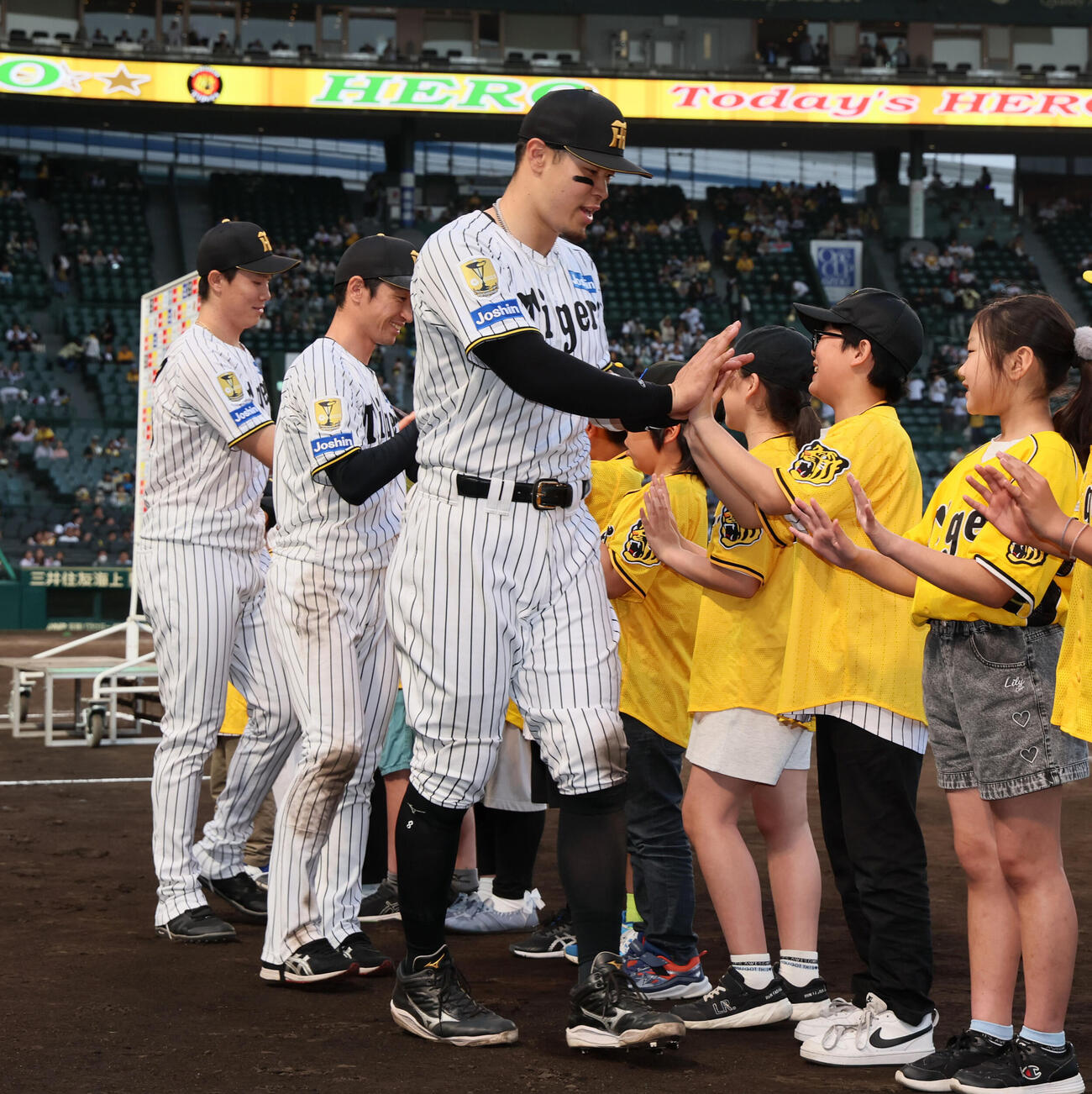 阪神対中日　ヒーローの左から阪神湯浅、近本、佐藤は待ち受ける子どもたちとタッチ（撮影・加藤哉）