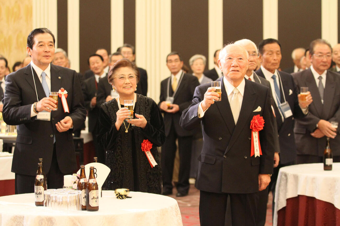2011年12月、出版記念祝賀会で乾杯する岡本伊三美さん（右）と美智子夫人。左は日本ハム梨田前監督