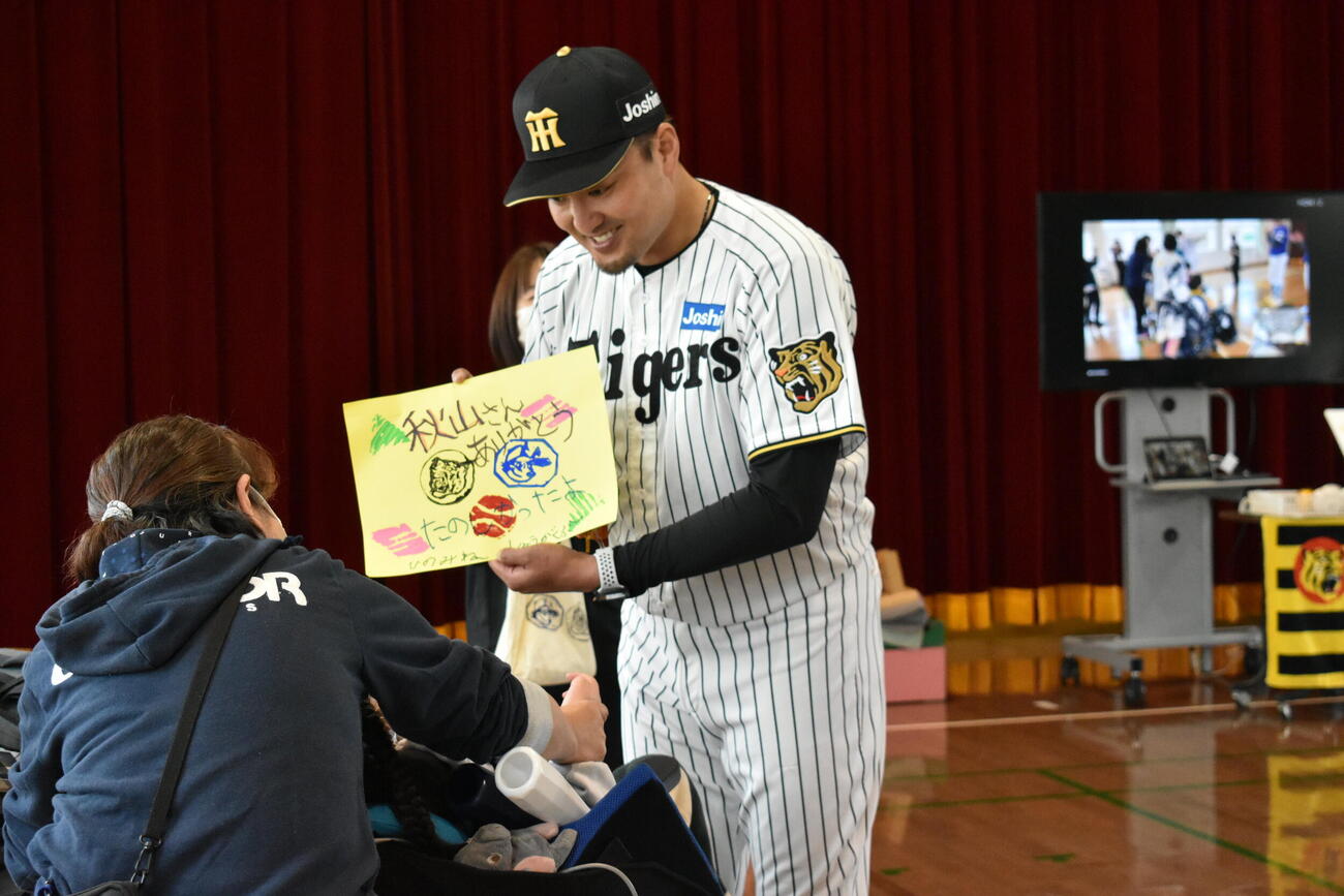 支援学校の生徒からプレゼントを受け取る阪神秋山BA（撮影・只松憲）