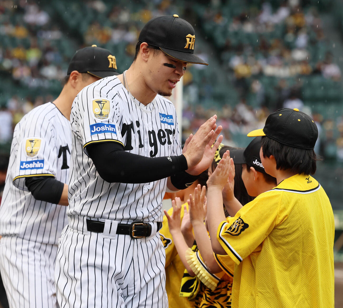 阪神対広島　広島に勝利しヒーローインタビューを受けたあと子どもたちとタッチする阪神佐藤輝明。左は大竹耕太郎（撮影・加藤哉）
