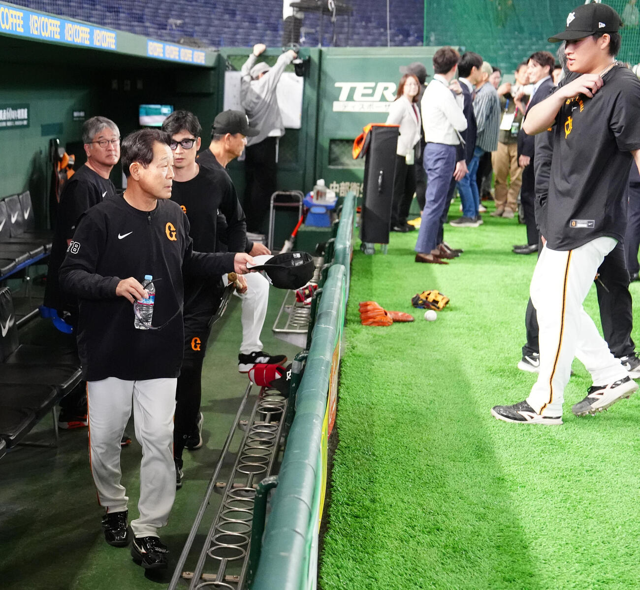 巨人対広島　試合前練習中、ボールが側頭部に当たり、ベンチ裏に引き揚げる巨人川相昌弘ディフェンスチーフコーチ（左手前）。右は増田陸（撮影・江口和貴）