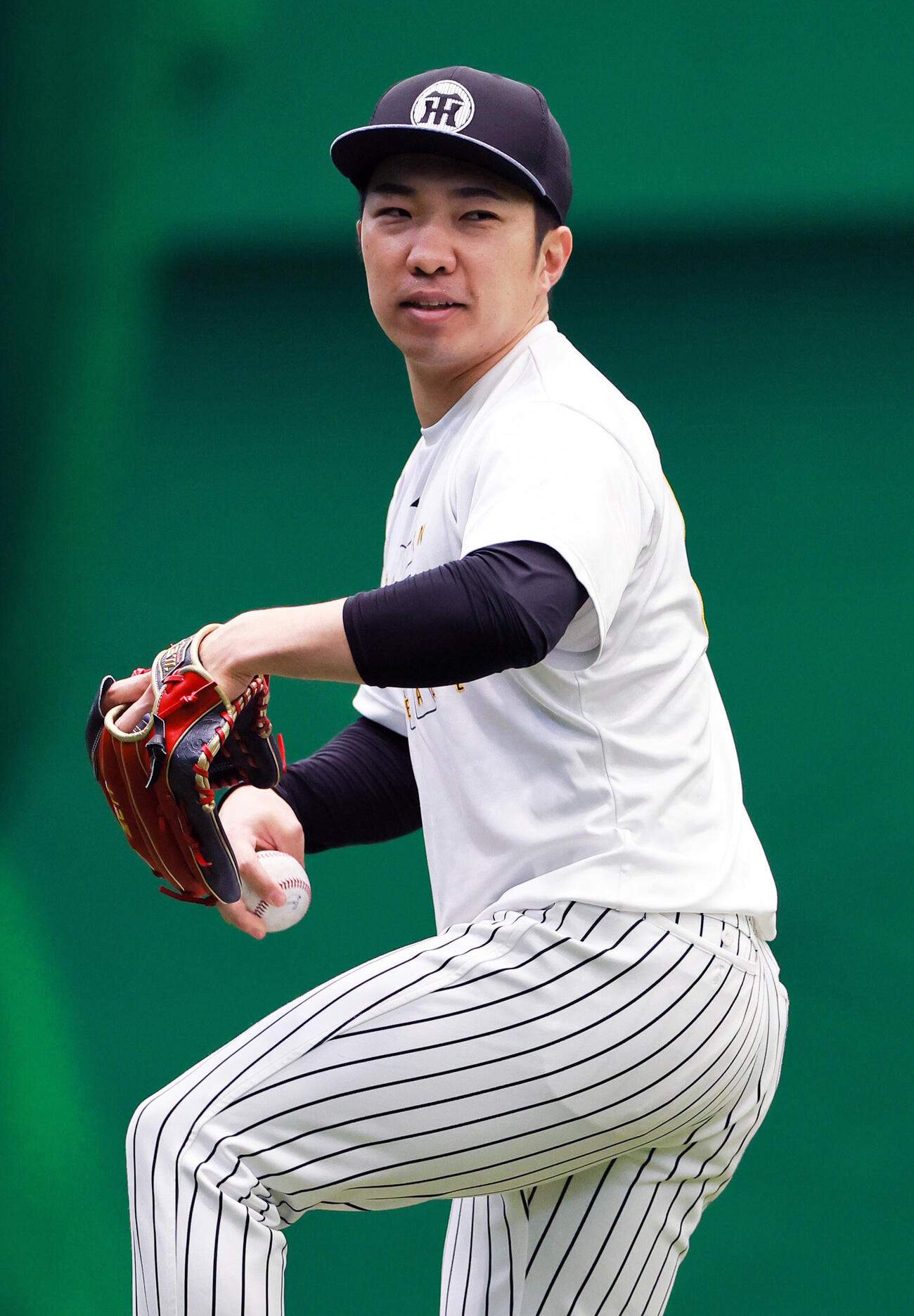 SGLスタジアムの室内でキャッチボールする阪神石井大智（撮影・上山淳一）