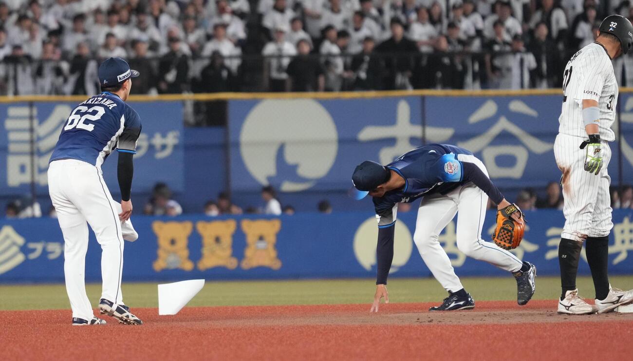 ロッテ対西武　3回裏ロッテ2死二塁､西武滝沢夏央遊撃手（左）と石井一成二塁手は強風のためグラウンドに舞い込んだ紙を回収する（撮影・小沢裕）